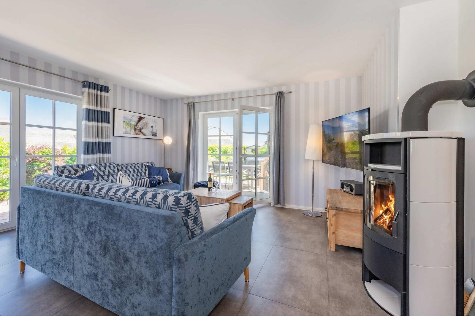 Wohnzimmer mit Sofa, Kamin und TV. Durchgänge zu Balkon und Garten.