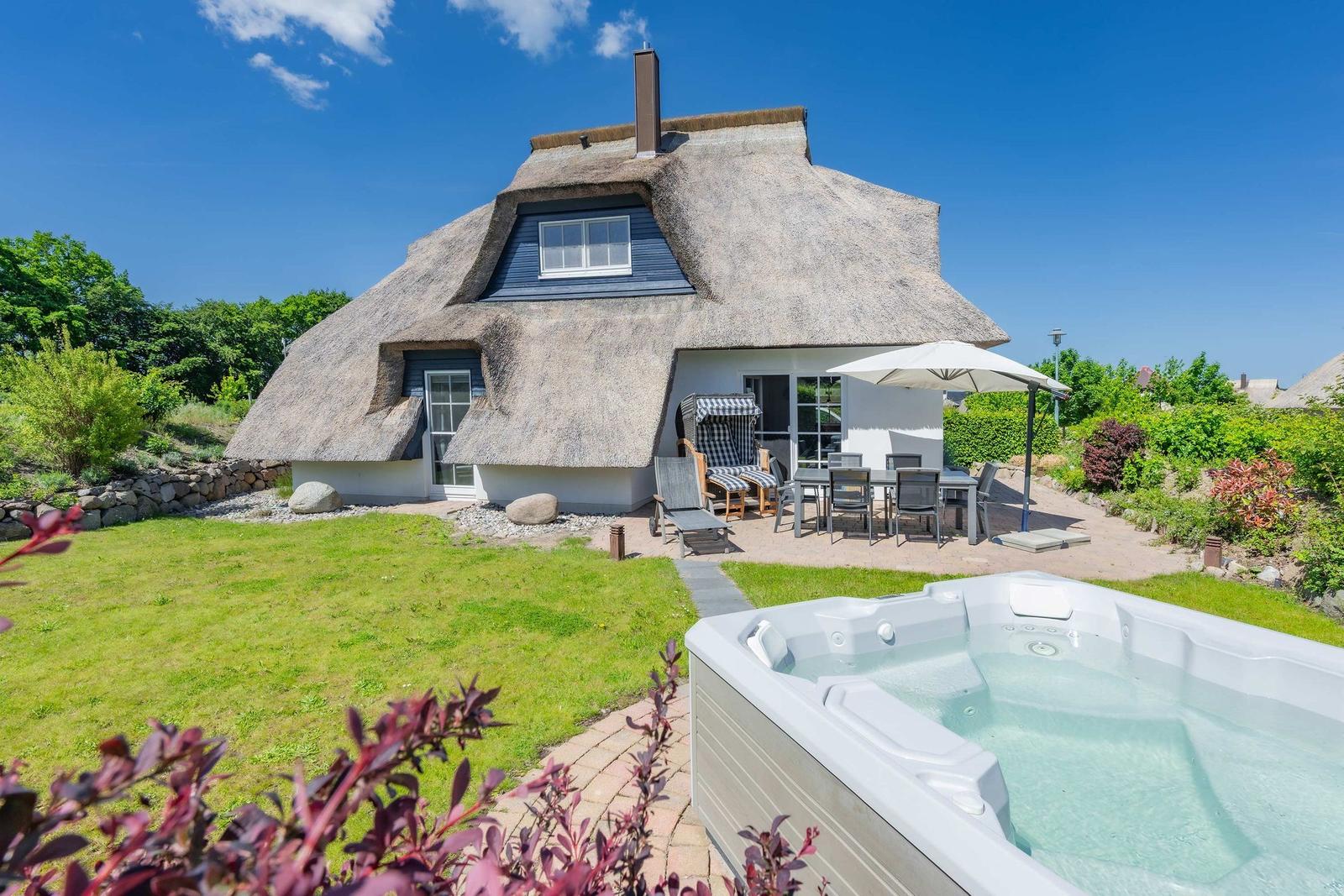 Dorfhaus mit Strohdach, Terrasse und Whirlpool im Garten.