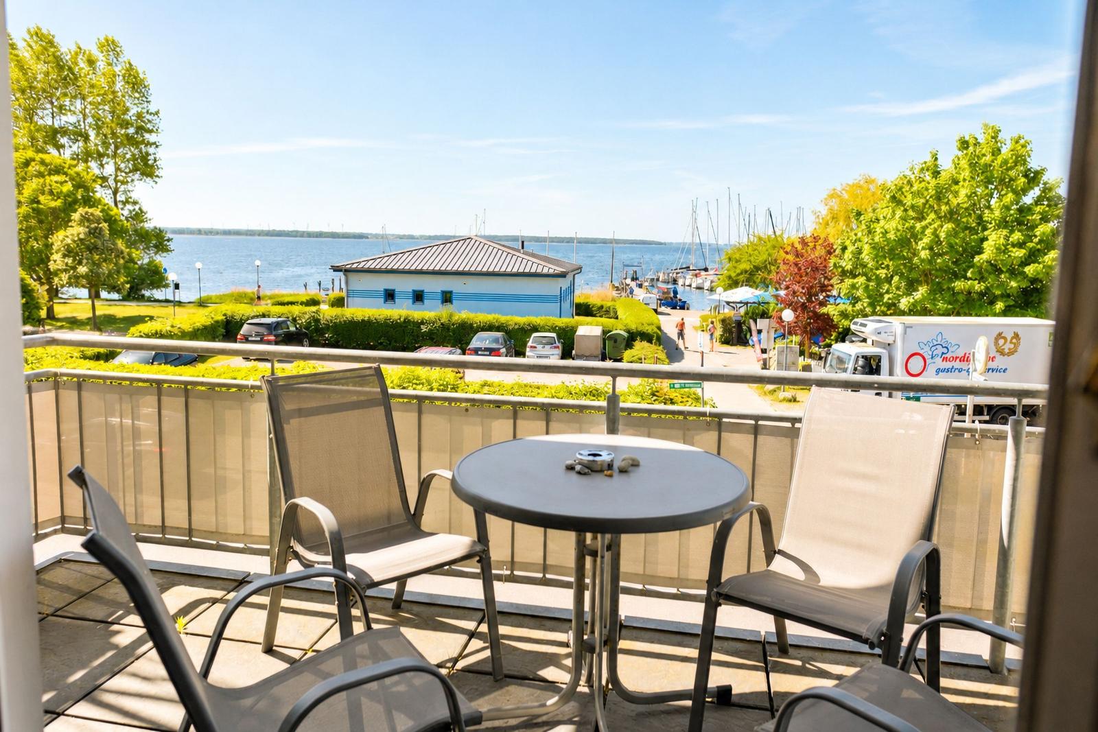 Terrasse mit Tisch und Stühlen, Blick auf Hafen und Wasser.