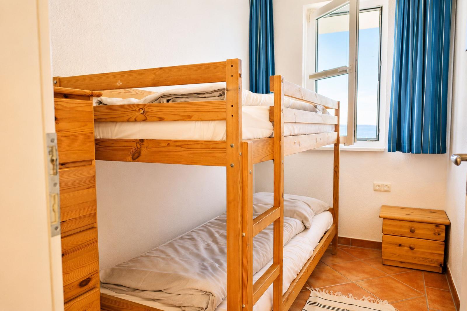 Ein Schlafzimmer mit einem Holzbett und einem Fenster mit Blick auf das Meer.