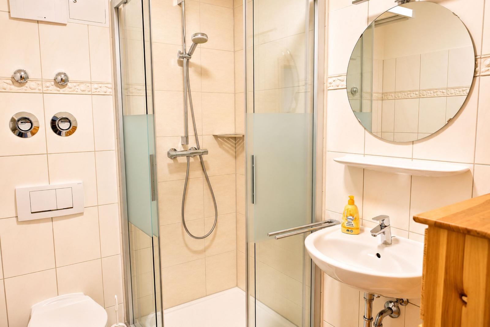 Badezimmer mit Dusche, Waschbecken und Spiegel