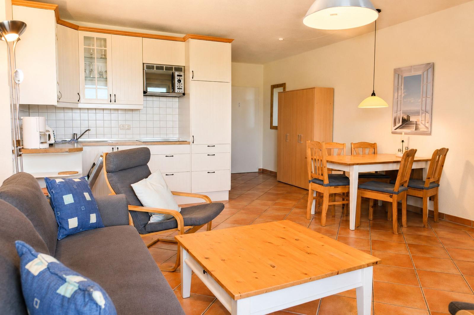 Wohn- und Essbereich mit Küchenzeile, Sofa, Esstisch und Holzmöbel.