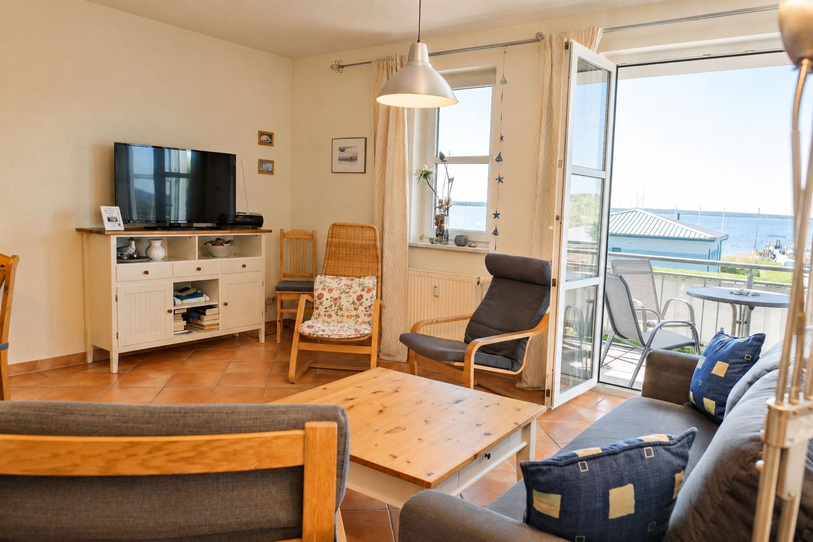Wohnzimmer mit TV, Sofa und Blick auf die Terrasse mit Meerblick.