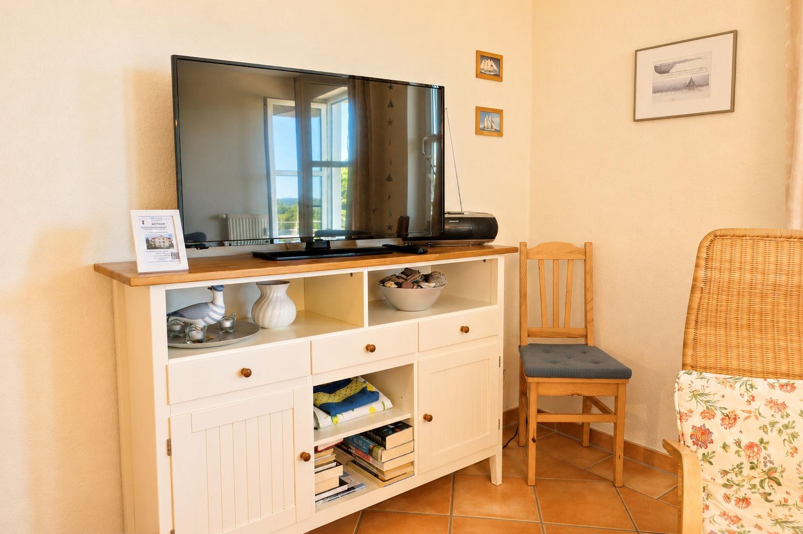 TV auf Holzschrank mit Stuhl und Sessel im Raum