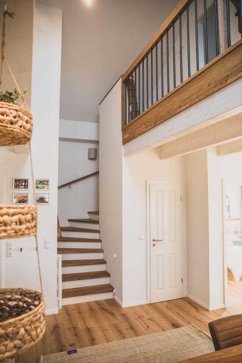 Haus mit Holztreppe, Balkon und hohen Wänden. Helle Räume mit Holzboden.