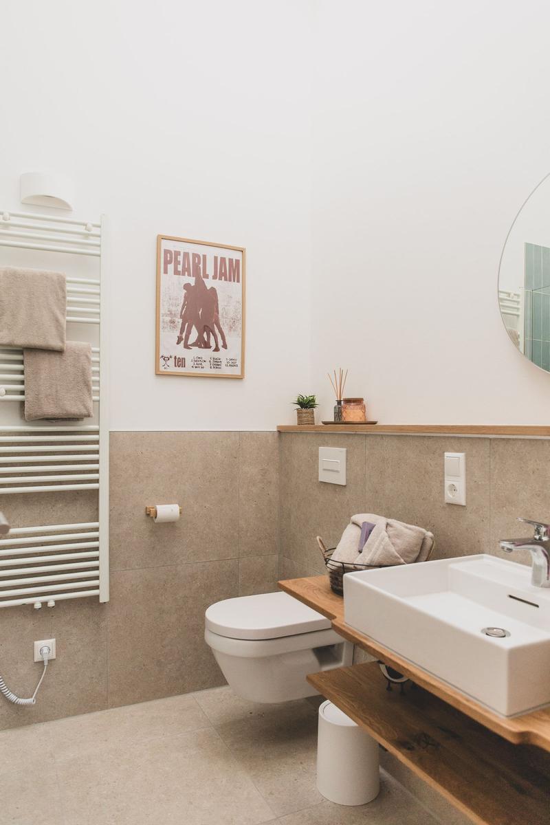 Badezimmer mit Toilette, Waschbecken und Heizkörper. Wandbild und Holzregal.