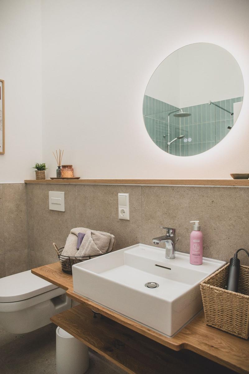 Badezimmer mit Waschbecken, Spiegel und Toilette. Holzoberfläche und Waschbecken.