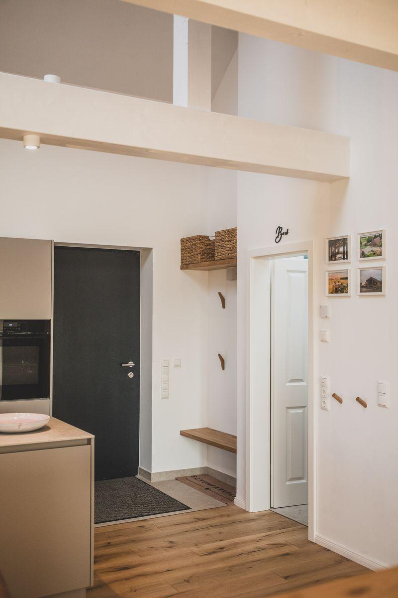 Eingangsbereich mit Küchenzeile, Holzboden und Tür zum Schlafzimmer.
