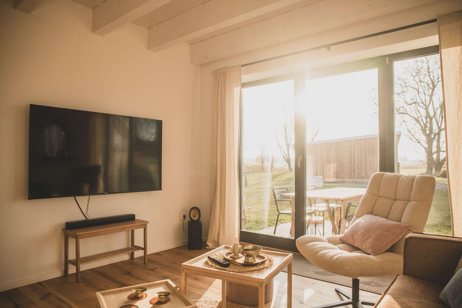 Wohnzimmer mit TV, Sitzgelegenheit und Blick auf die Terrasse.