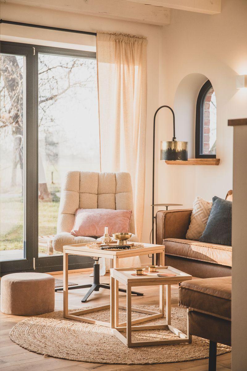 Wohnzimmer mit Sitzgelegenheiten, Tisch, Teppich und Fenster zum Garten.