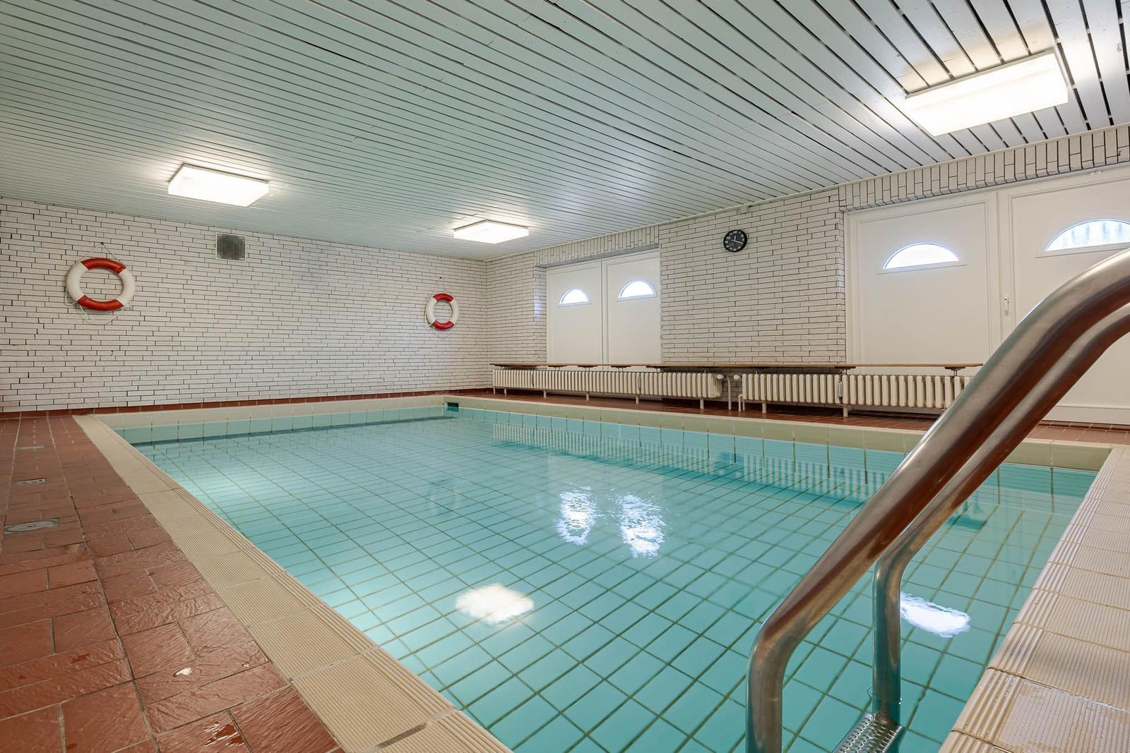 Indirect lighting illuminates the indoor pool with red floor and white walls.