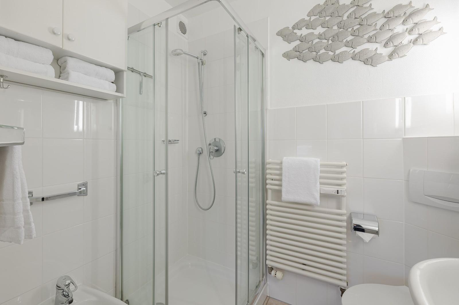 Bathroom with shower, towel rack, and wall decoration of fish.