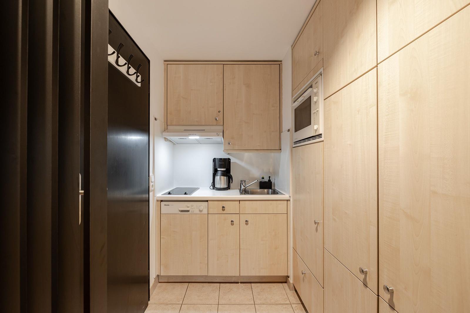 Kitchen with wooden cabinets, sink, coffee maker, and built-in oven.