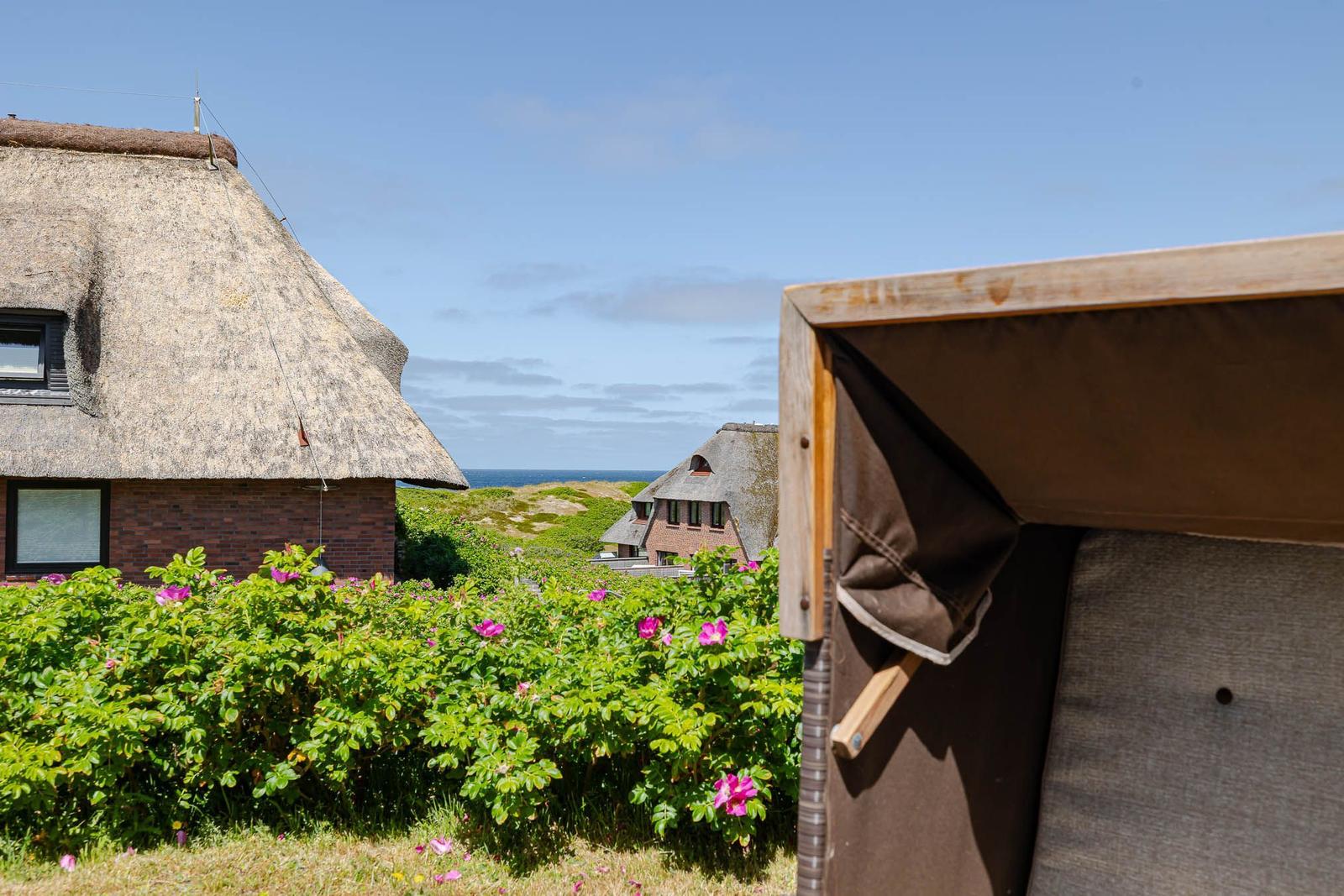 Dachhütte mit Blick auf das Meer und Blumenbeet