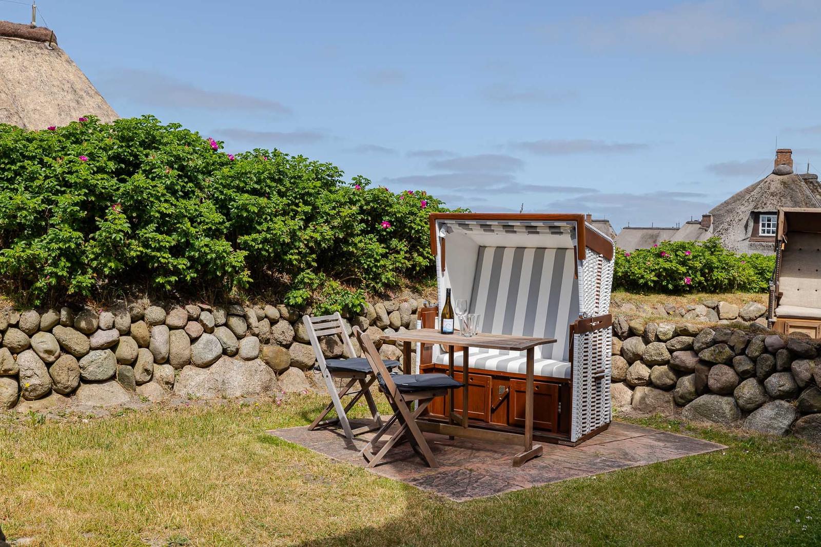 Ein Strandkorb mit Tisch und Stühlen auf einer Terrasse.
