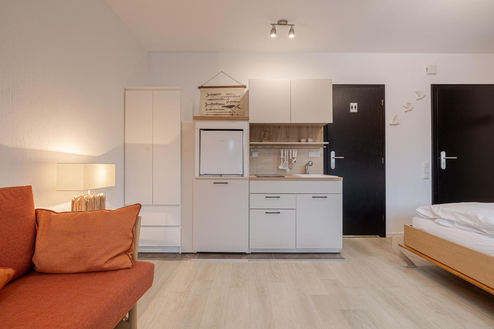 Wohnung mit Schlafzimmer, Küchenzeile und Sofa.