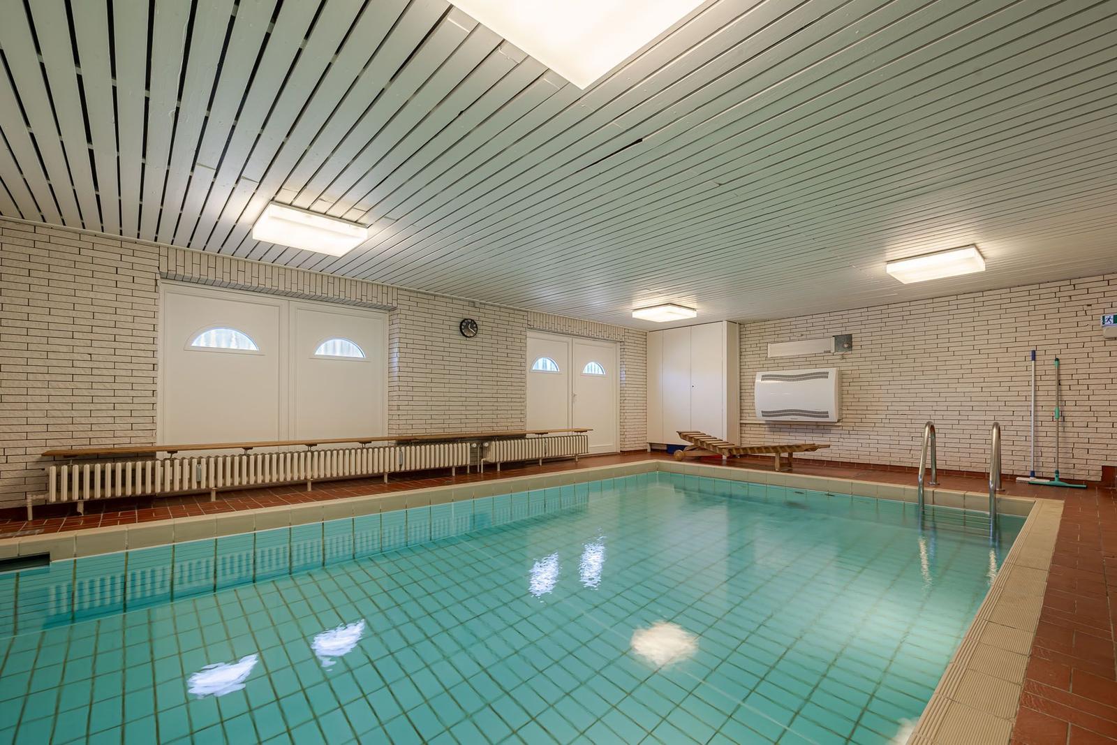 Innenpool mit Holzliegen und Heizung an der Wand