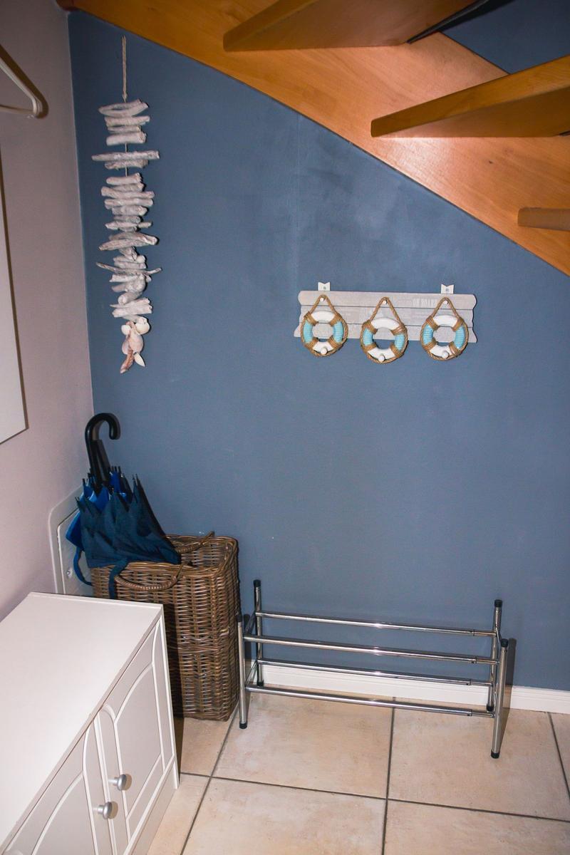 Eingangsbereich mit blauer Wand, Regal mit Rettungsringen und Korb mit Regenschirm.