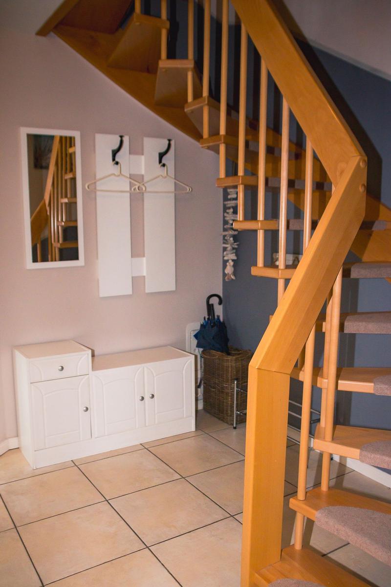 Haus mit Holztreppe, Schuhschrank und Spiegel an der Wand.