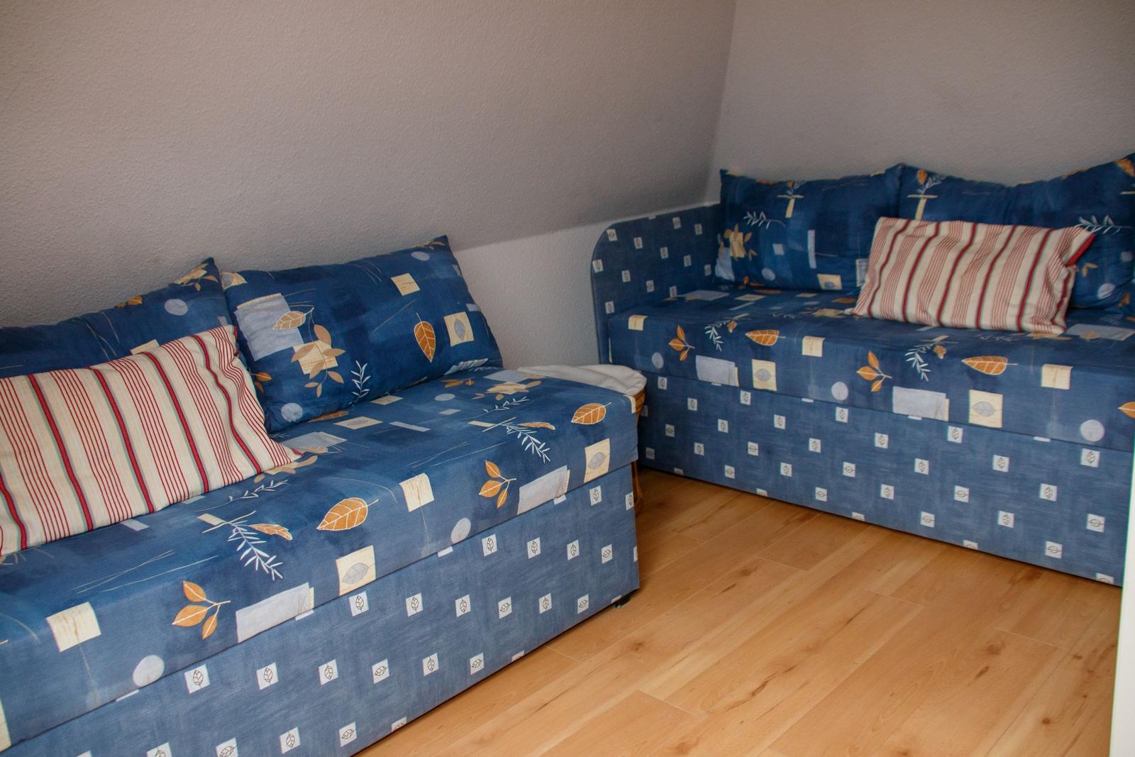 Zwei Sofas mit blauem Bezugsstoff und Kissen auf Holzboden.