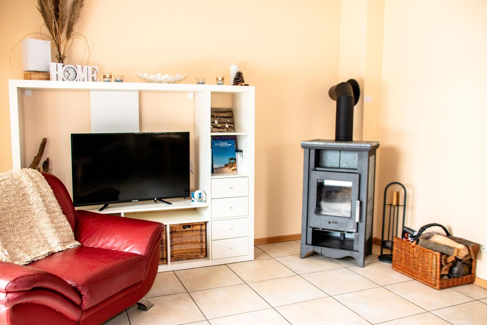 Ein Wohnzimmer mit rotem Sofa, TV-Möbel und Holzofen.