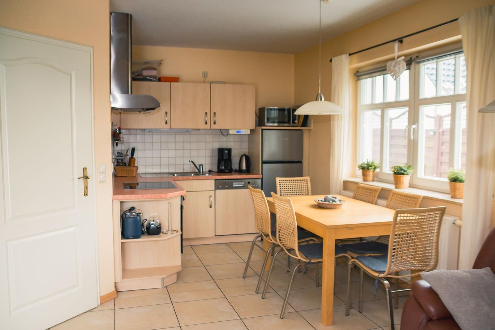 Küche mit Essbereich, Holztisch, Stühle und Fenster mit Pflanzen.