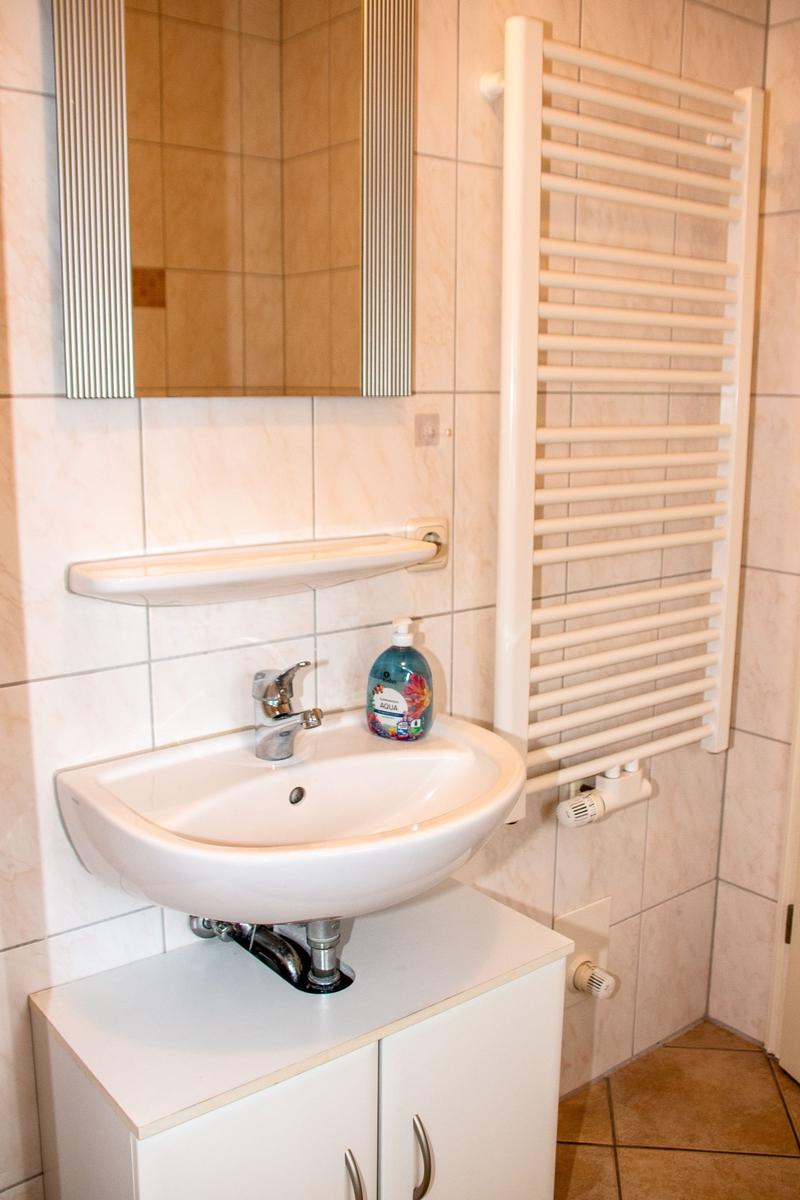 Badezimmer mit Waschbecken, Spiegel und Heizkörper