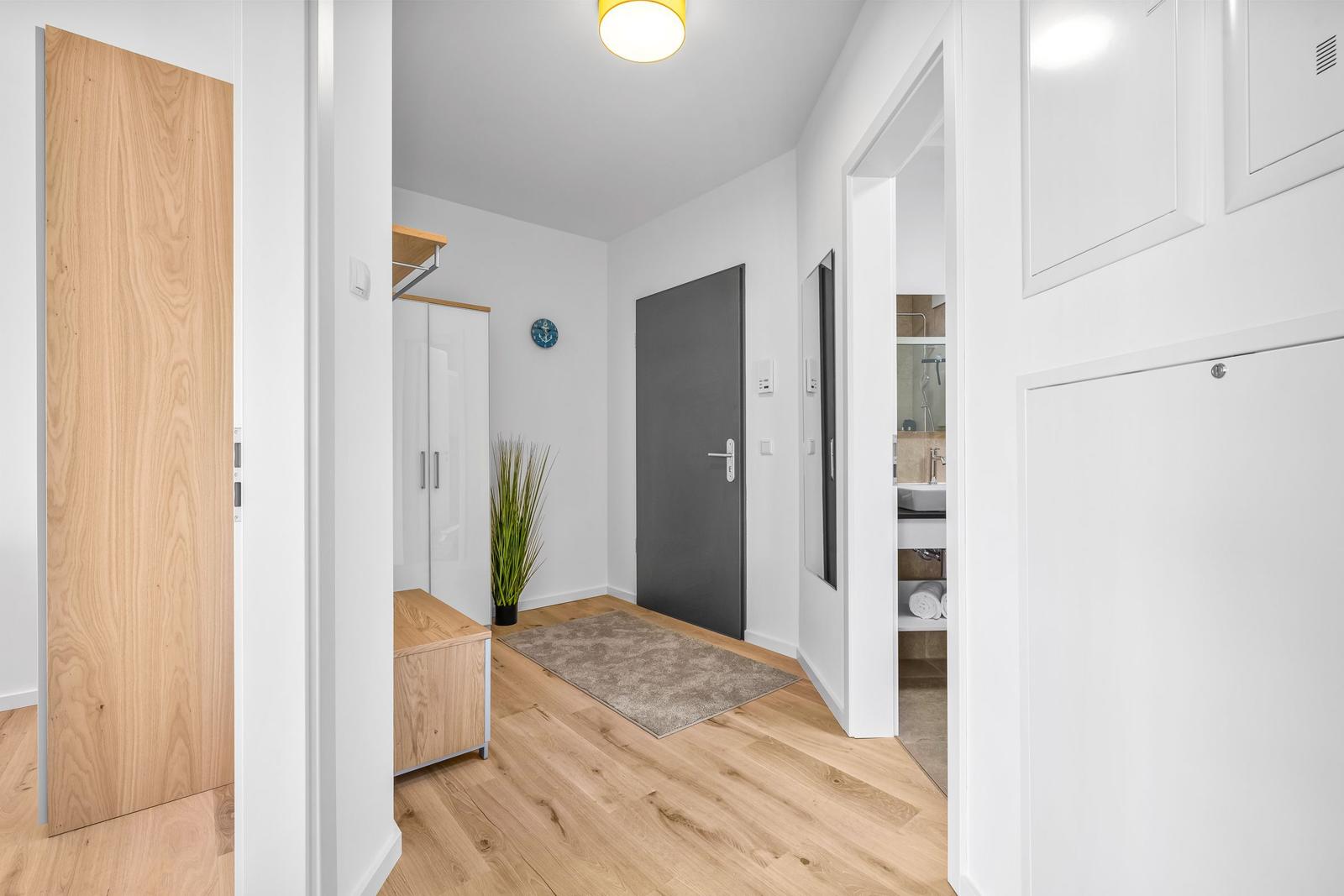 Eingangsbereich mit Holzboden, Schrank und Blick in Bad und Schlafzimmer.