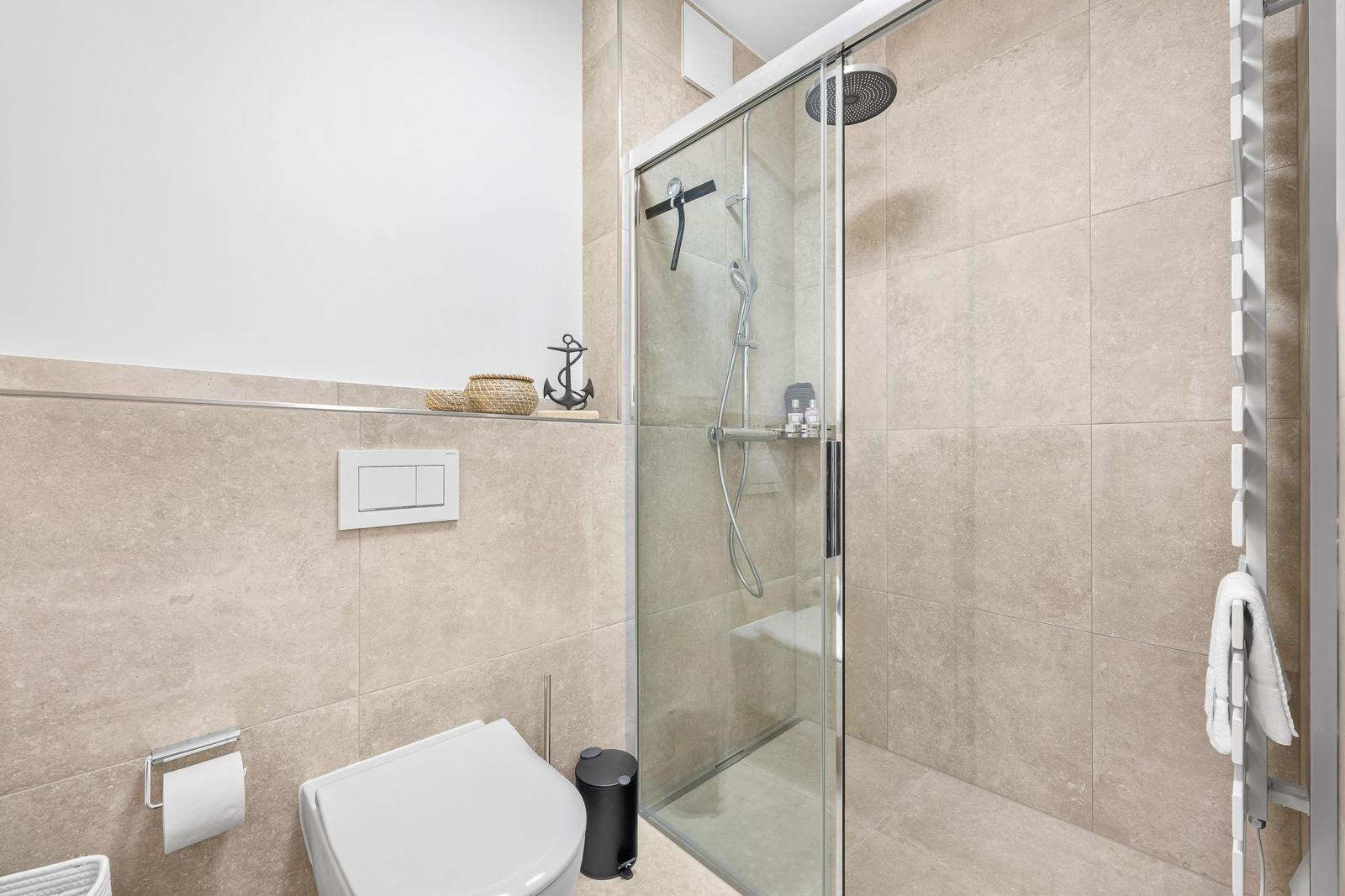 Badezimmer mit Dusche, Toilette und Handtuchhalter.