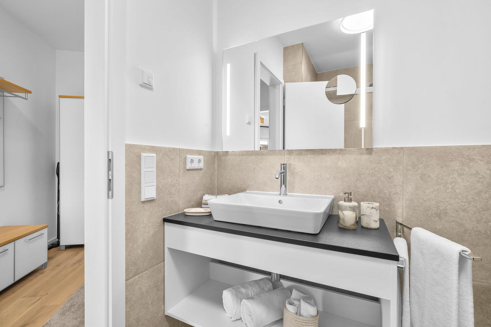 Badezimmer mit Waschbecken, Spiegel und Handtüchern