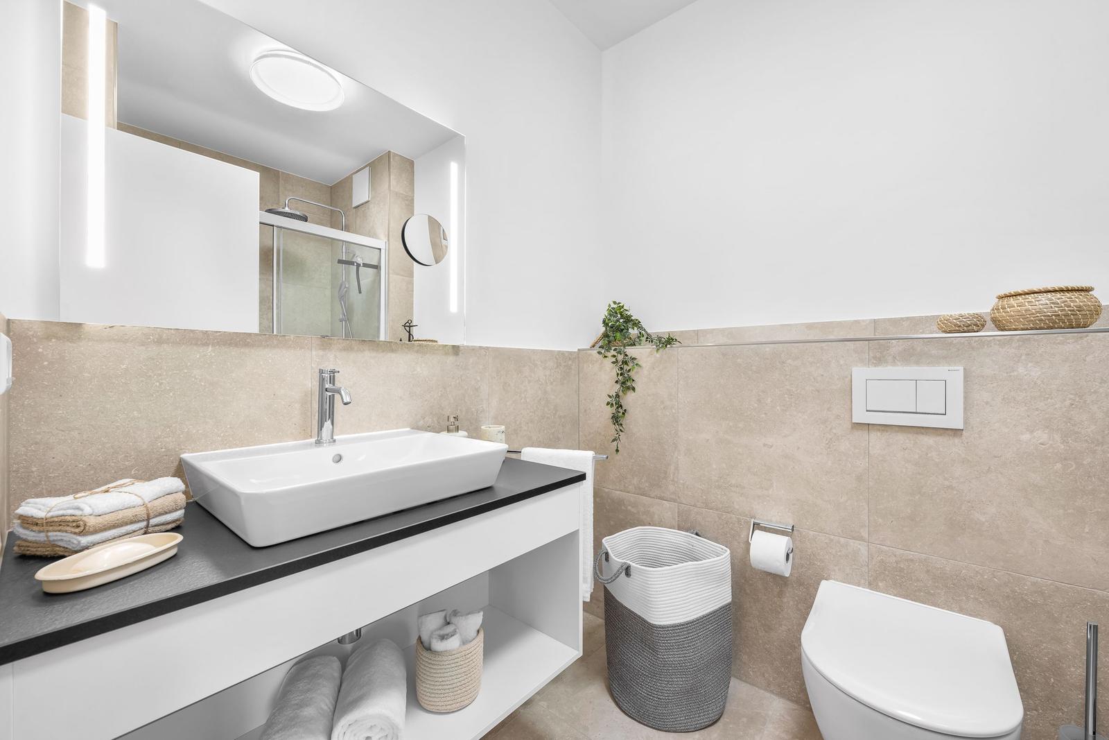 Bad mit Waschbecken, Dusche, Toilette und Handtuchhalter.