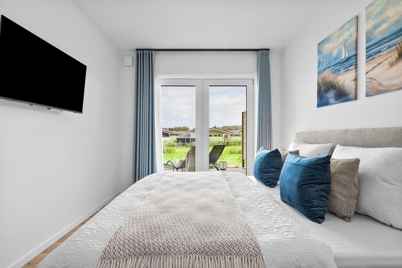Schlafzimmer mit Bett, TV und Balkonblick