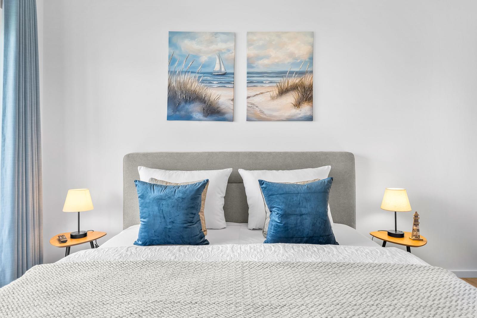 Schlafzimmer mit Bett, zwei Nachttischen und Wandbildern an der Wand.