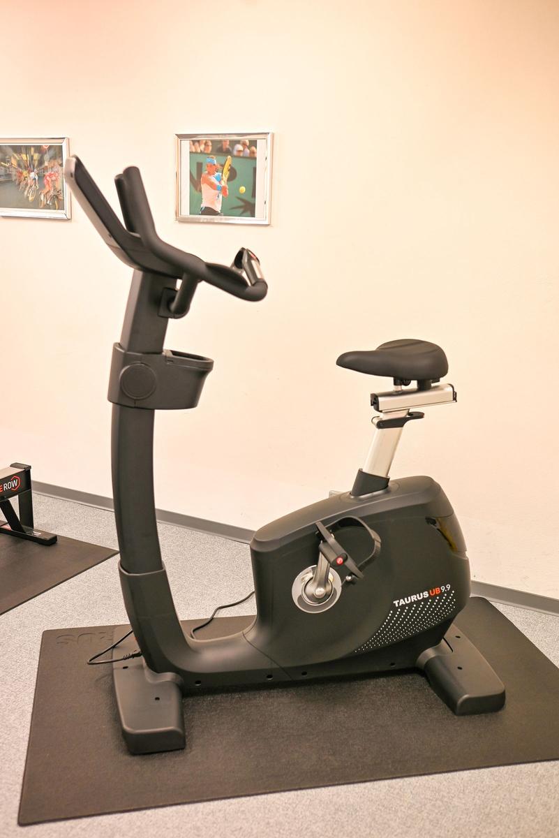 Fitnessrad auf dunkler Matte in einem Raum mit Wandbildern.