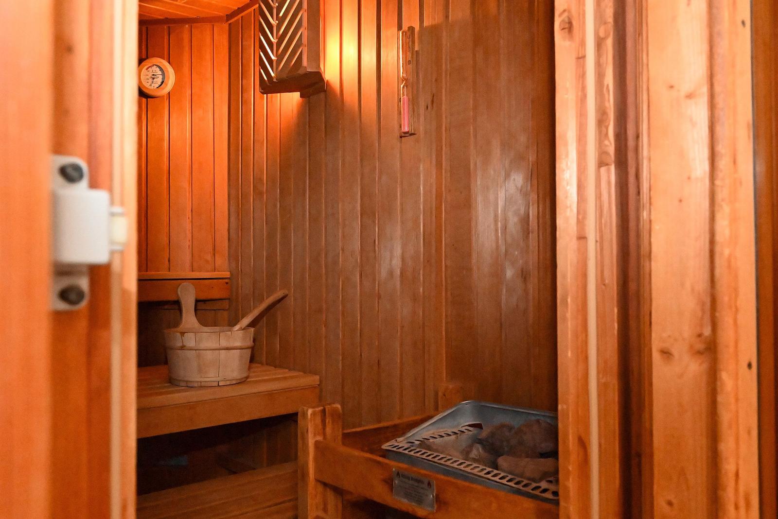 Sauna mit Holzwand, Sitzbank, Eimer und Heizung.