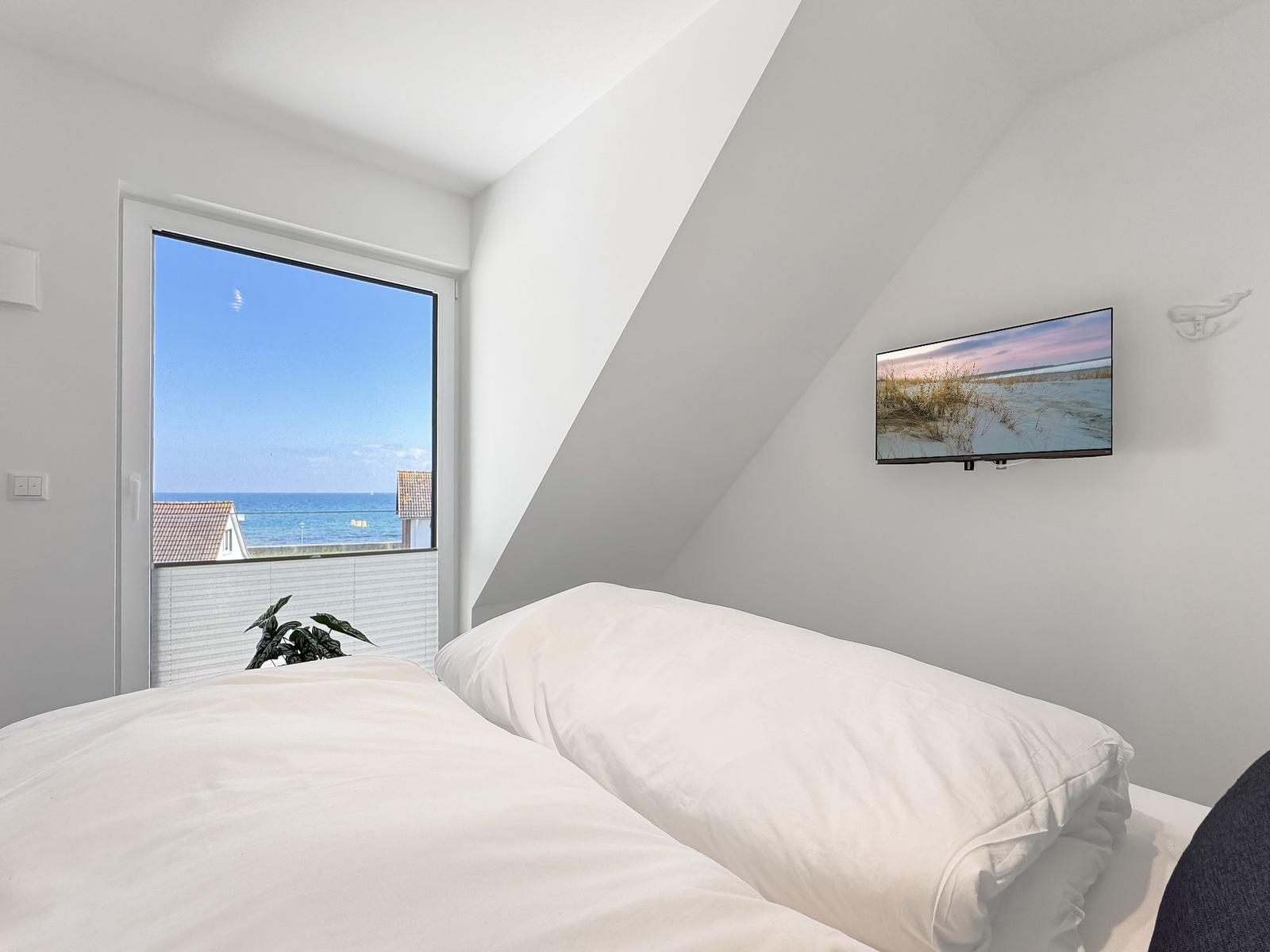 Schlafzimmer mit Blick aufs Meer und Wand-TV.