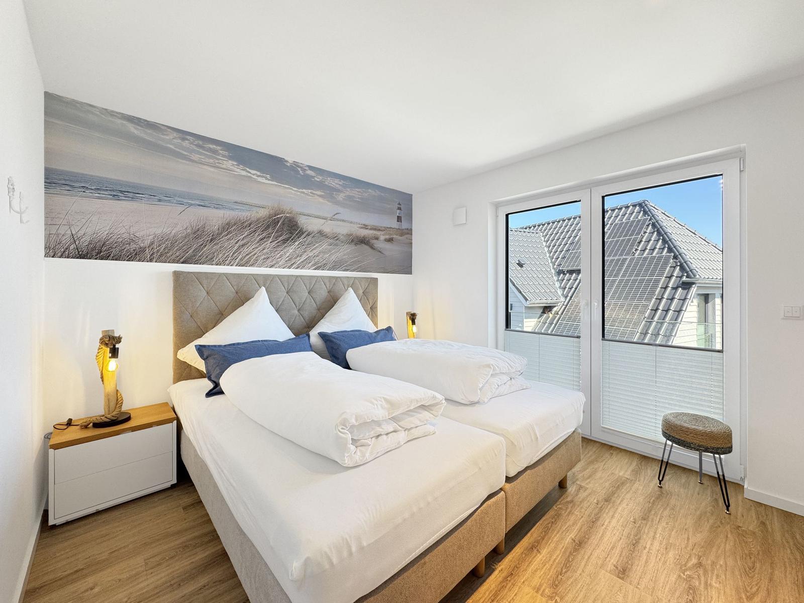 Schlafzimmer mit Doppelbett, Wandbild und Balkontür.