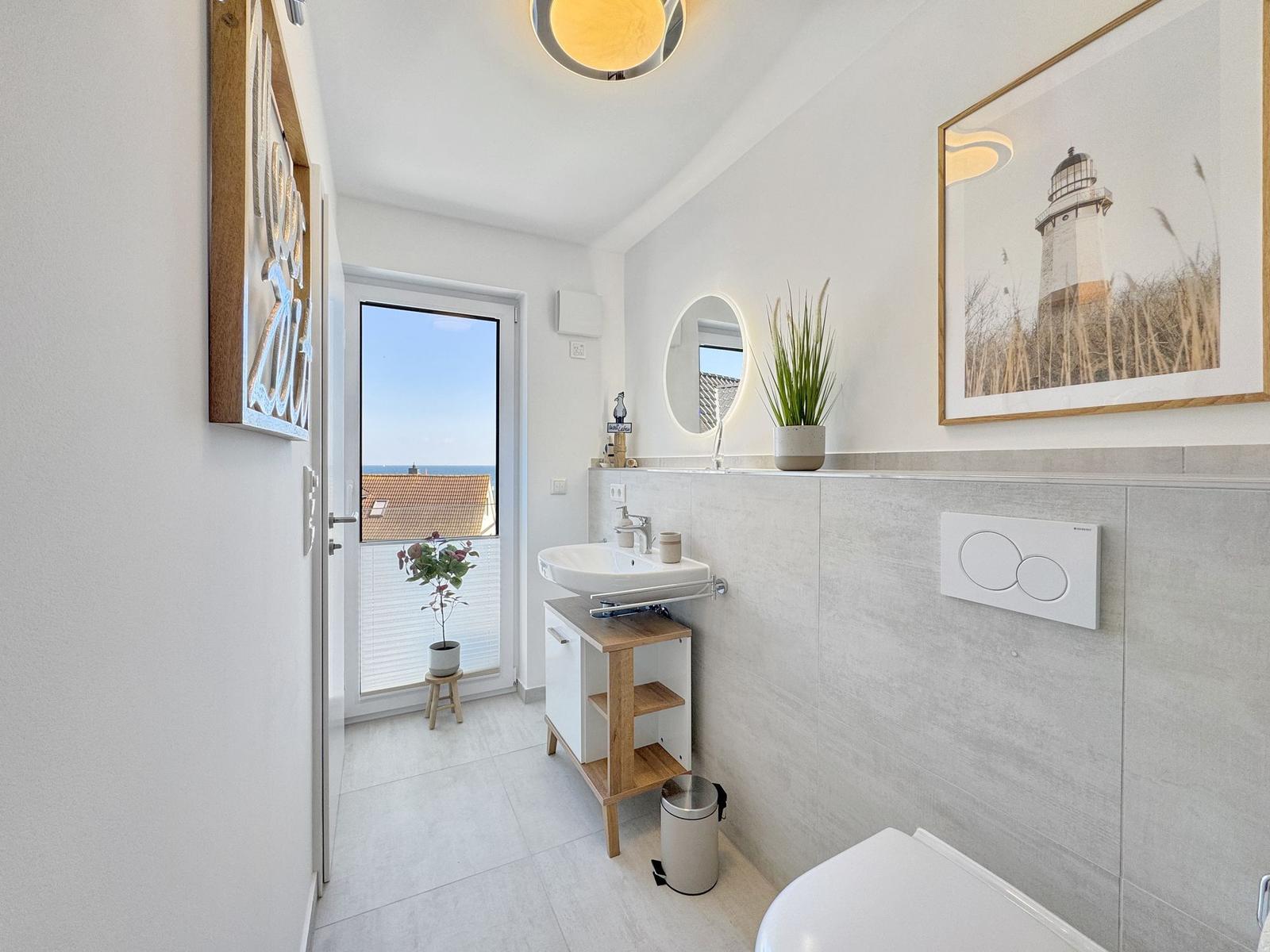 Badezimmer mit Waschbecken, Toilette und Blick aufs Meer.