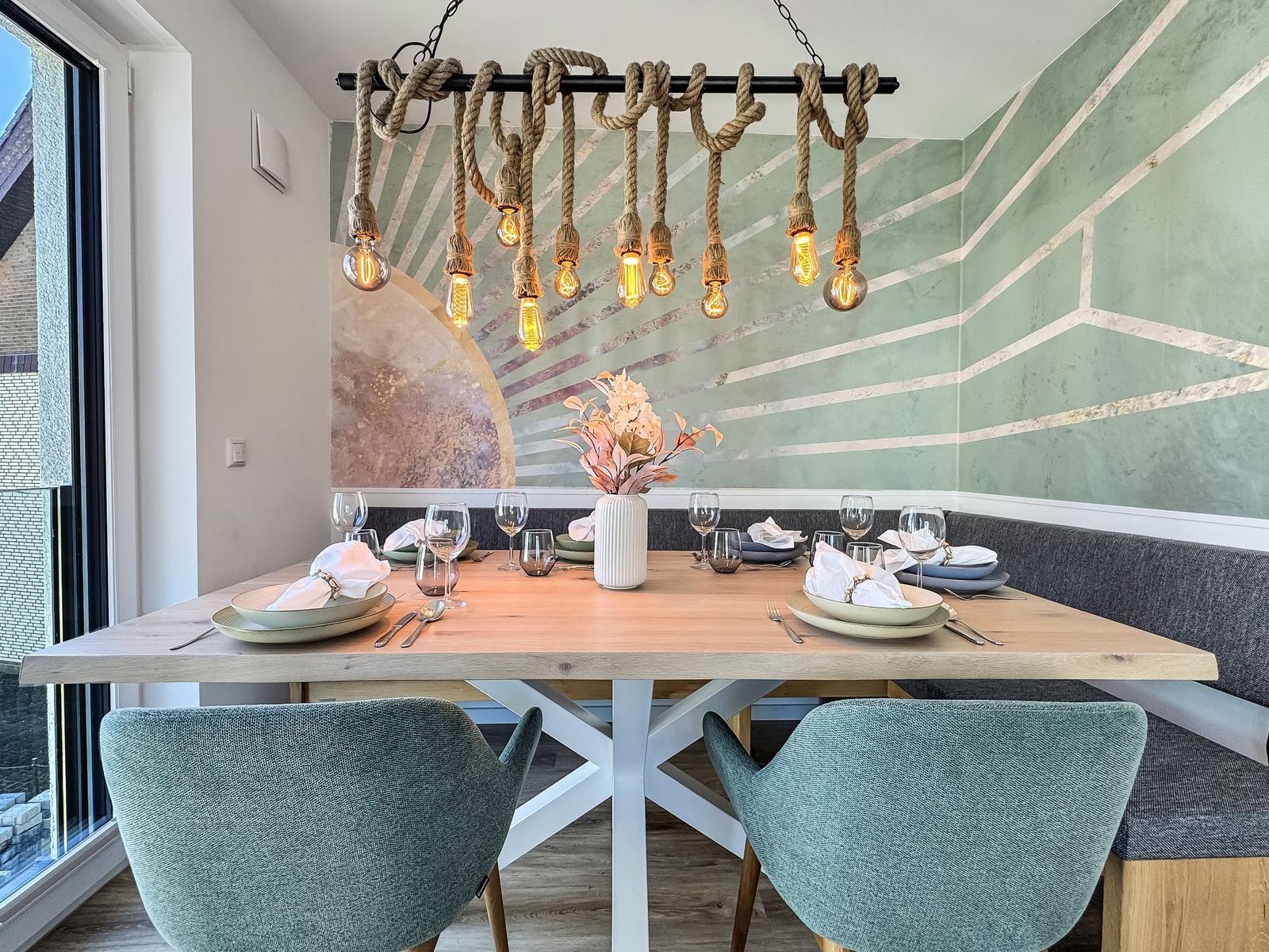 Esszimmer mit Holztisch, Stühlen und einer Deckenleuchte mit Seilbefestigung.