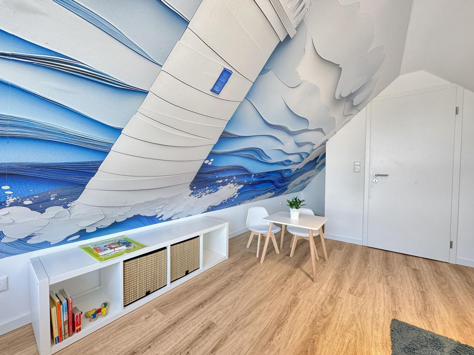 Raum mit Wandbild, Tisch, Stühlen und Regal