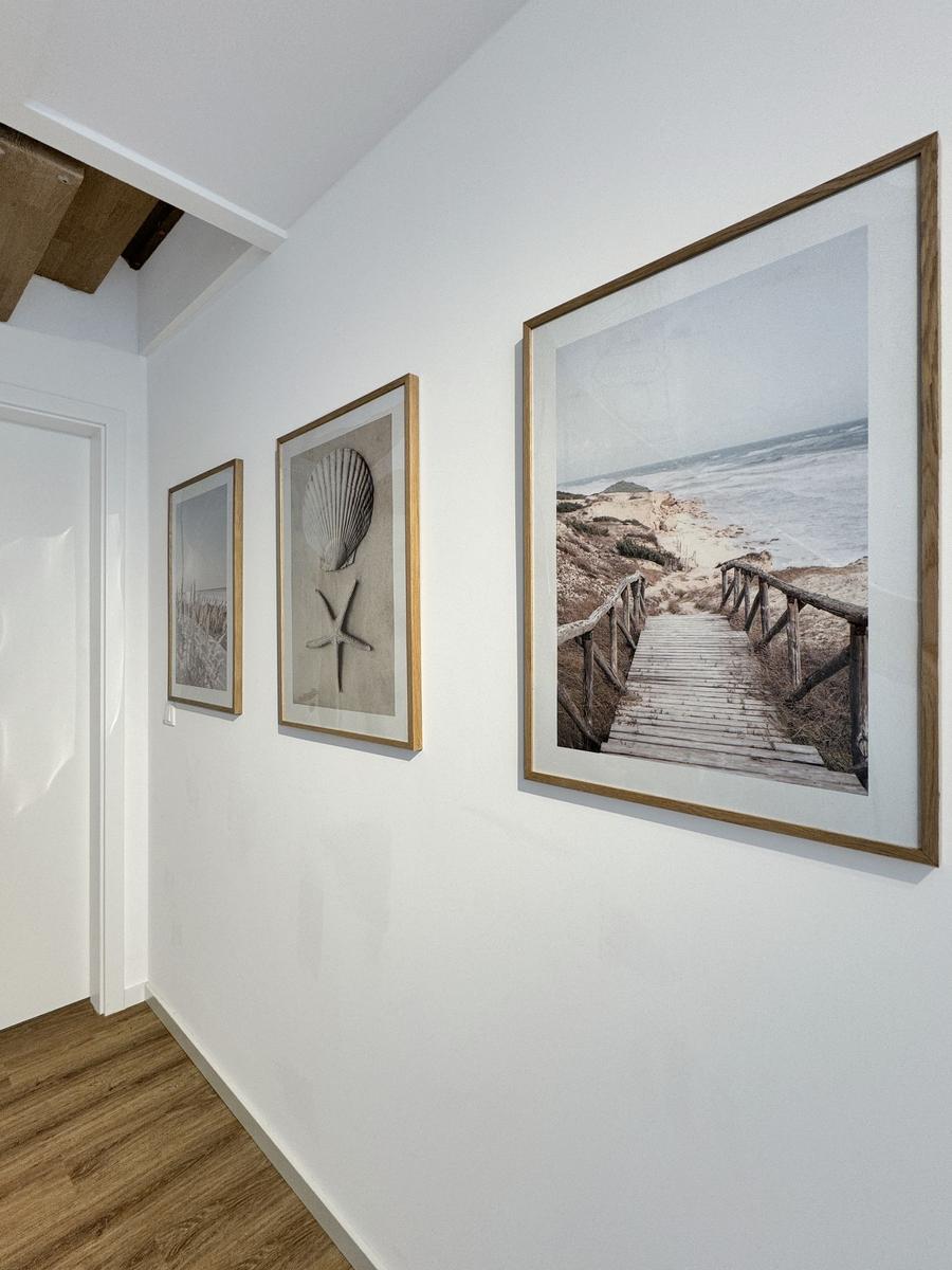 Wand mit drei gerahmten Strandbildern und Holzfußboden.