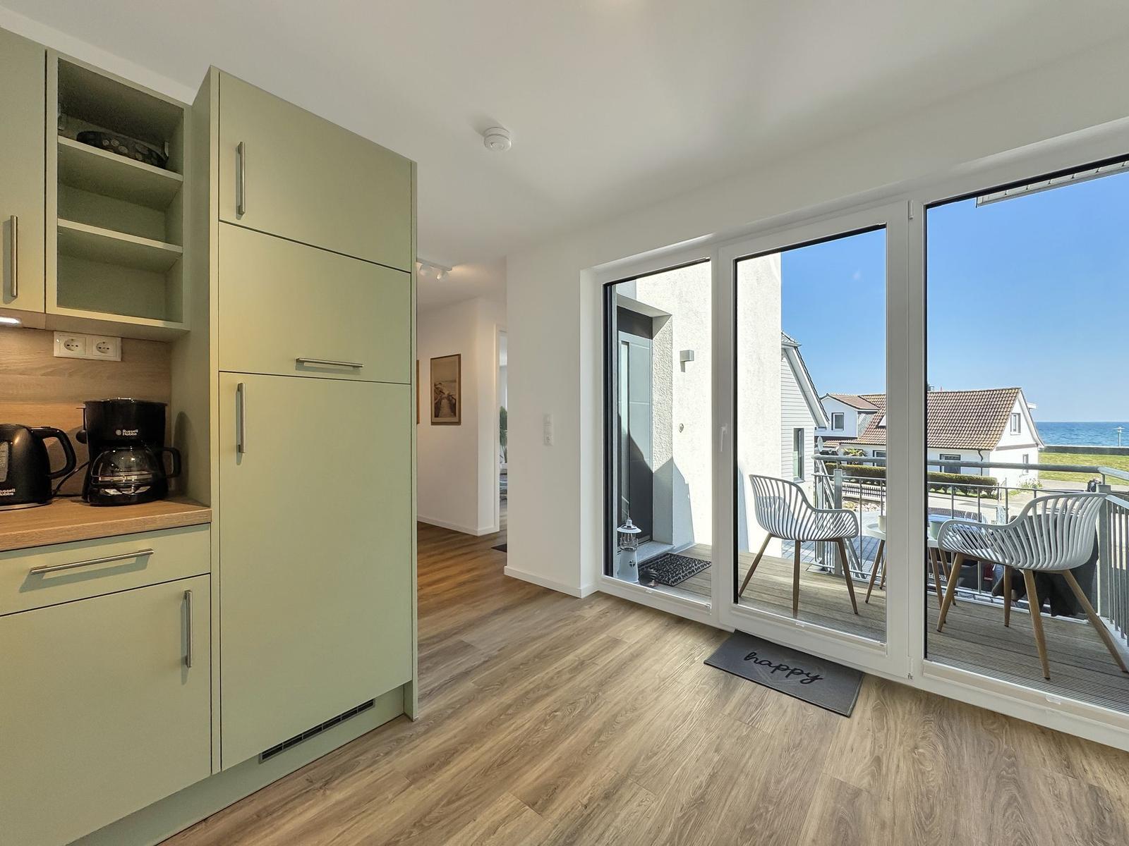 Küche mit Balkon und Meerblick. Moderne Einrichtung und Holzboden.