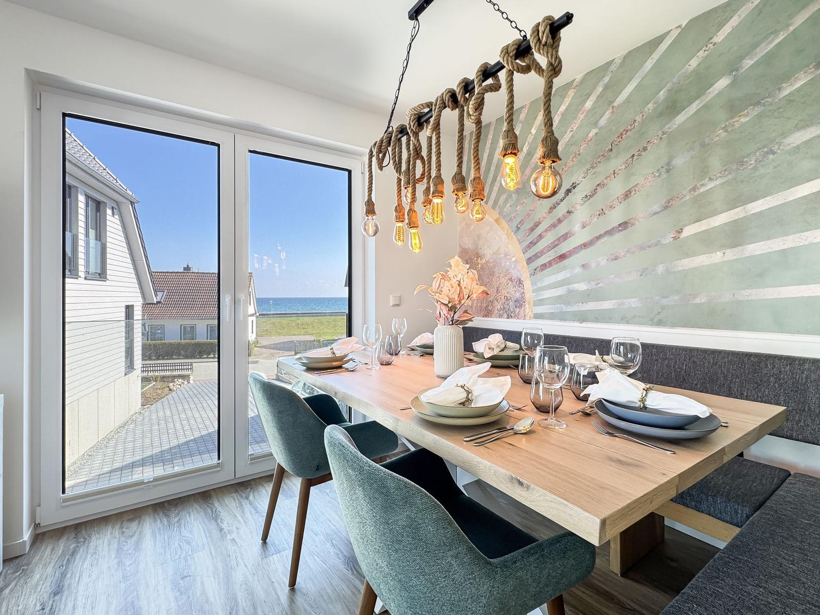 Essbereich mit Holztisch, Stühlen und Blick aufs Meer.