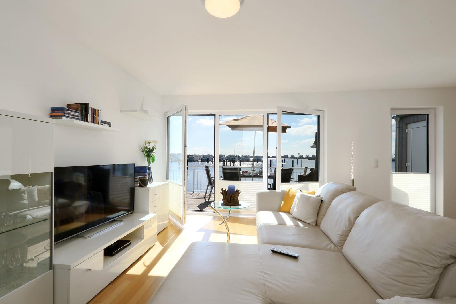 Wohnzimmer mit Sofa, Fernseher und Blick auf den Hafen.