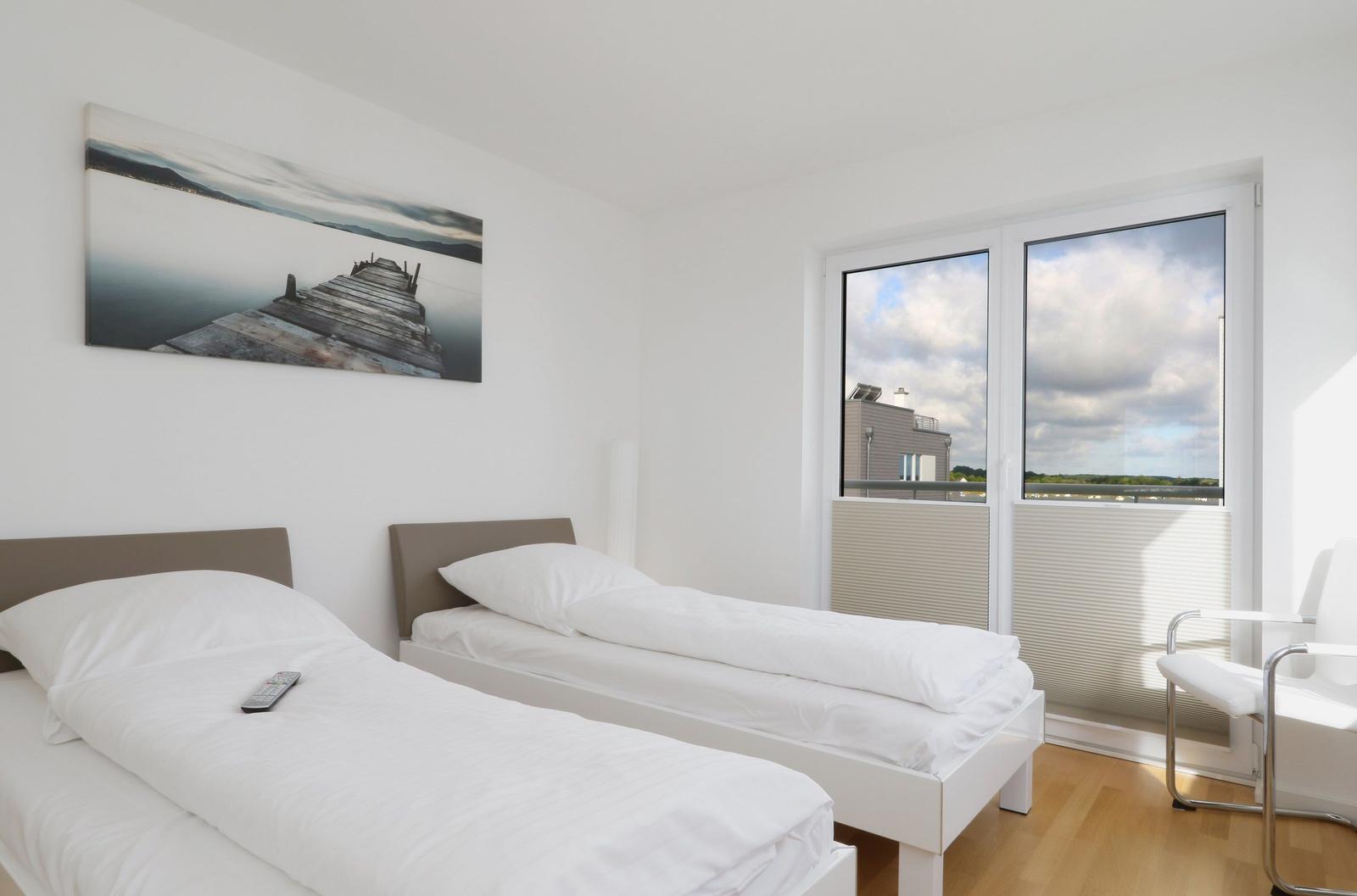 Zwei Einzelbetten, Wandbild und Fenster mit Blick auf Gebäude und Himmel.
