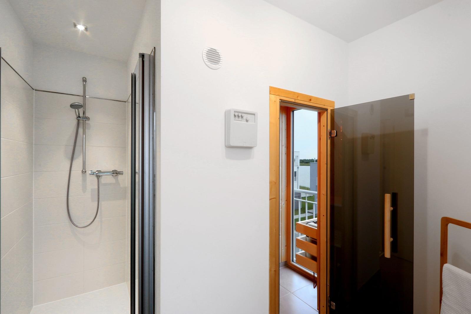 Dusche mit Glaswand, Sauna mit Holzrahmen und Balkonansicht