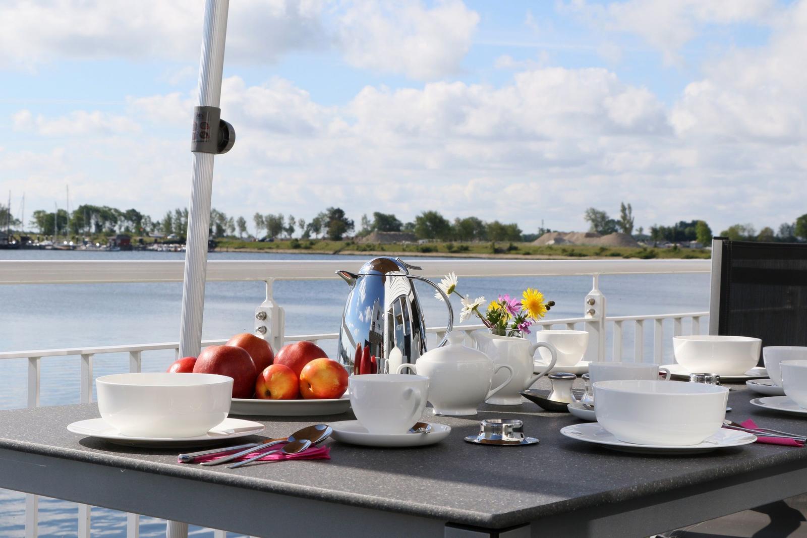 Frühstückstisch auf Terrasse mit Blick auf Wasser und Himmel.