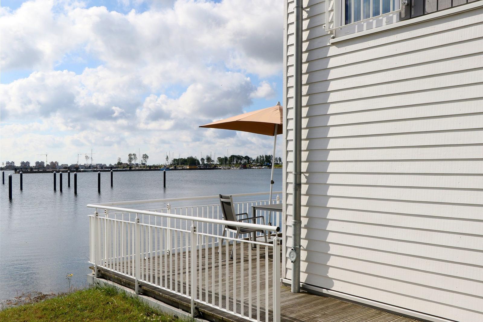 Terrasse mit Sonnenschirm und Stuhl am Wasser