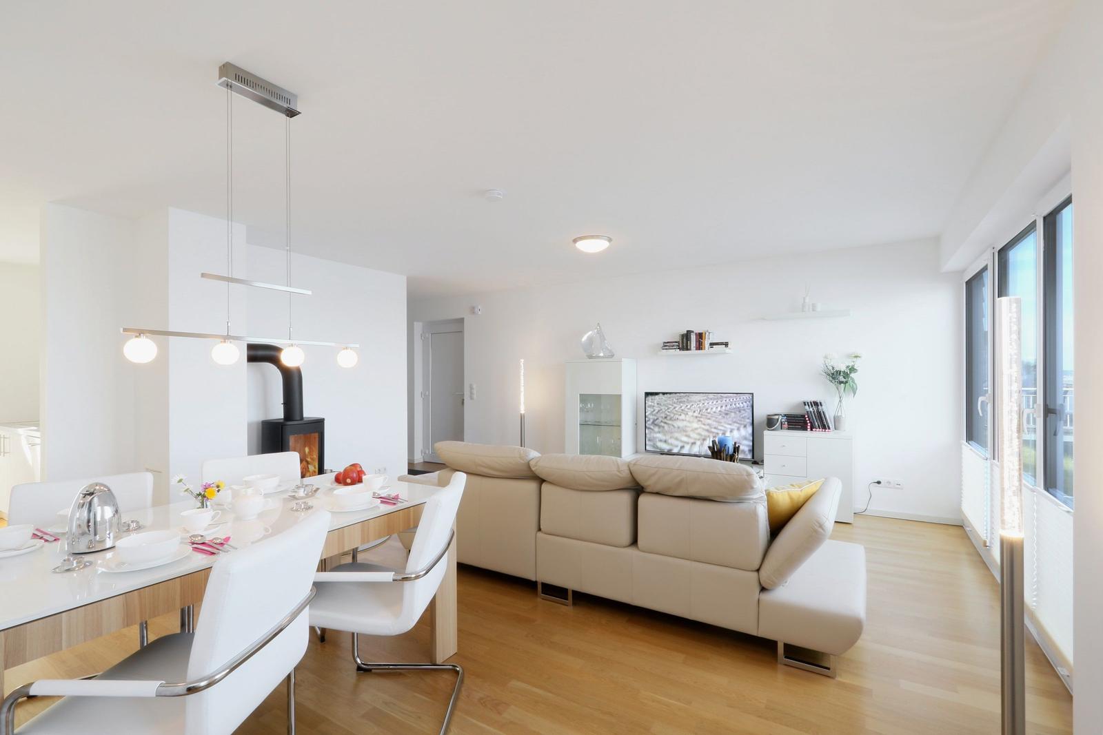 Wohn- und Essbereich mit Sofa, Esstisch und Kaminofen.