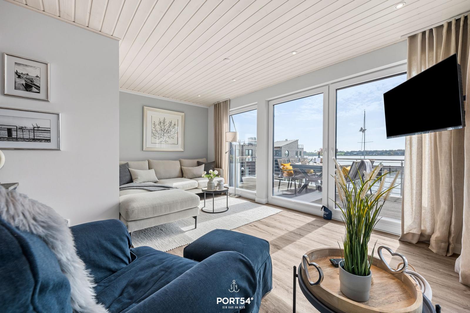 Wohnzimmer mit Sofa, Fernseher und Blick auf Terrasse